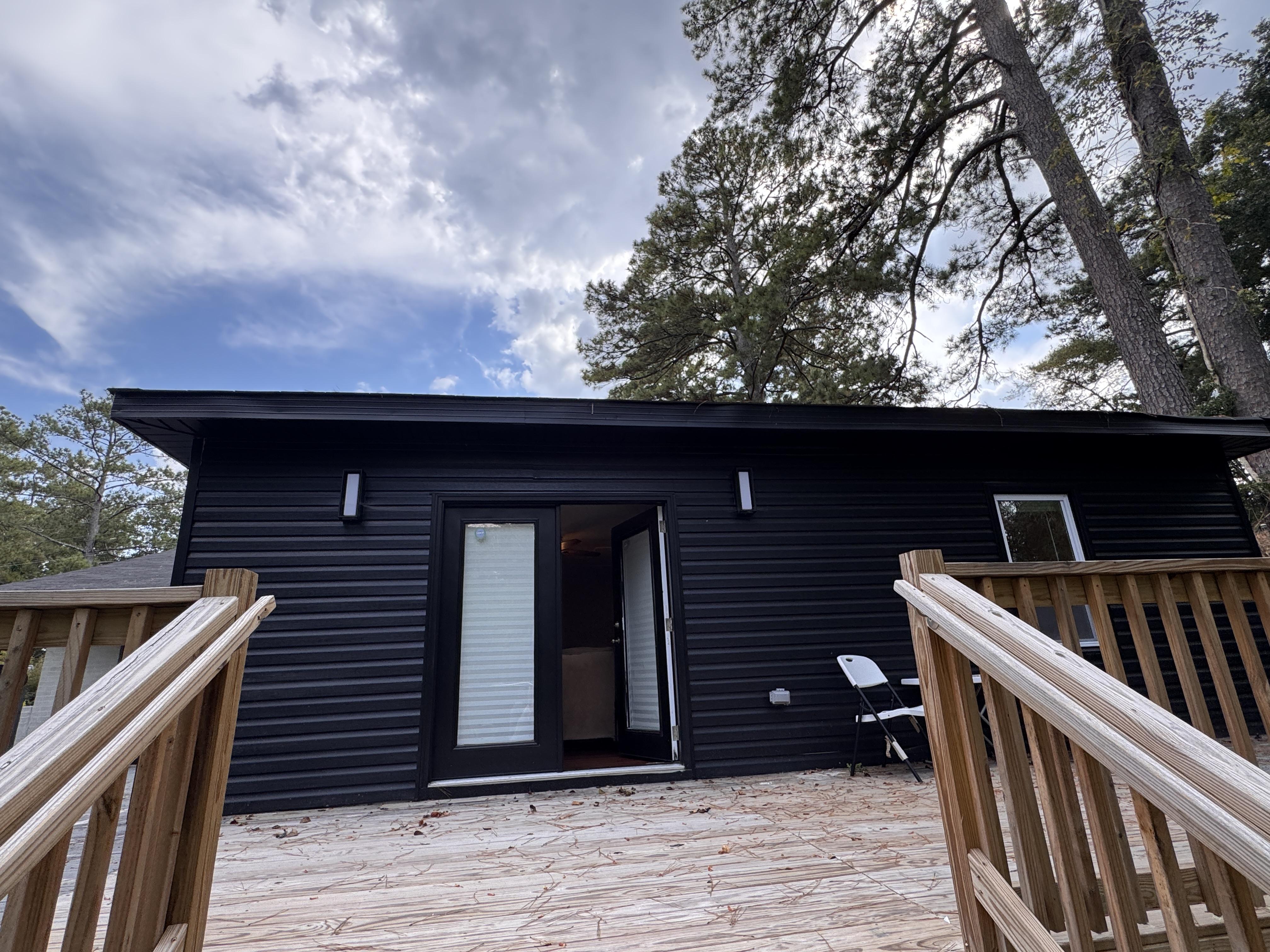 Rebuilt home exterior with modern black siding and wooden deck