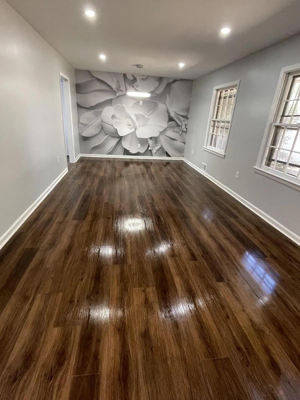 Renovated room with dark hardwood floors and floral wall mural