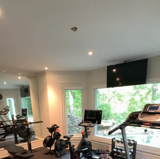 Restored home gym with treadmills, mirrors, and large windows
