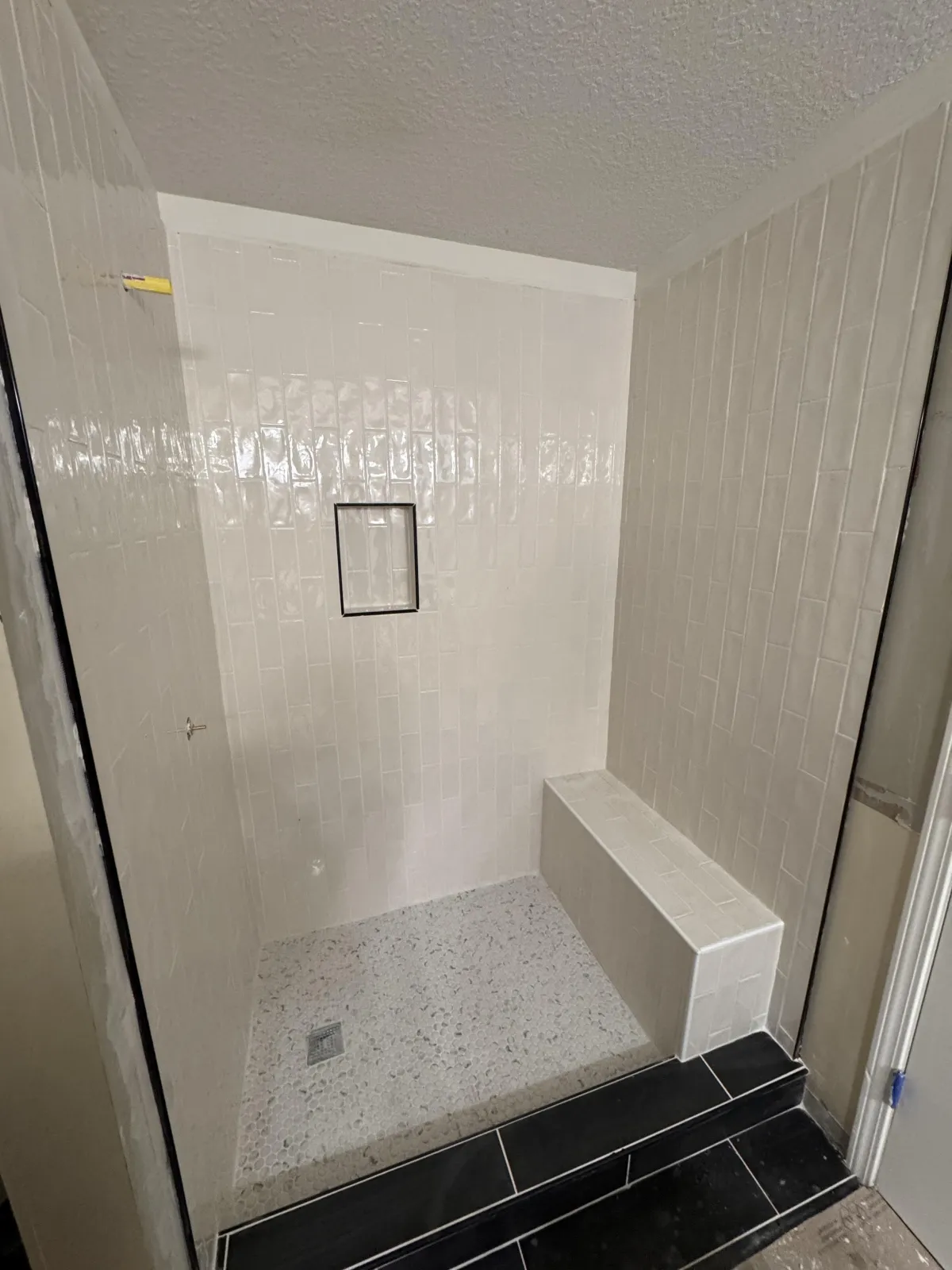 Walk-in shower remodel with white subway tile and pebble floor