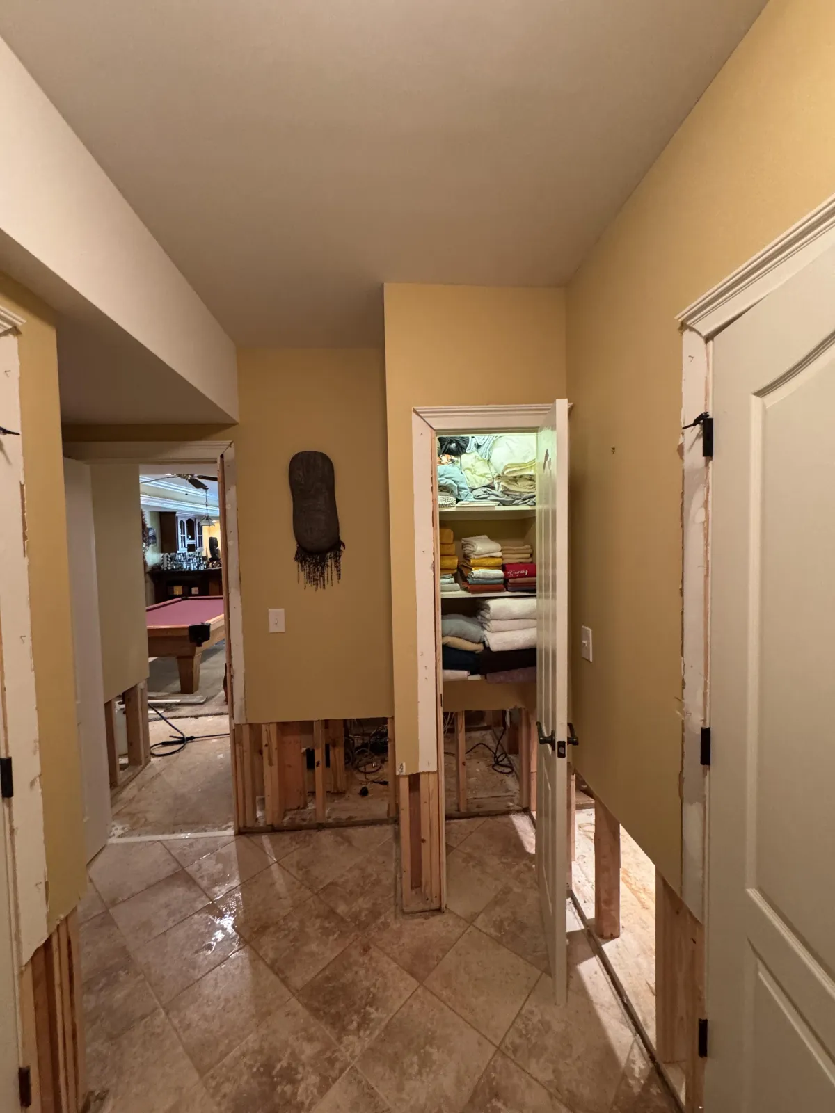 Hallway in mid-mitigation with drywall cut at base showing studs